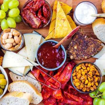 A tapas platter containing meats, nuts, cheese and jams.