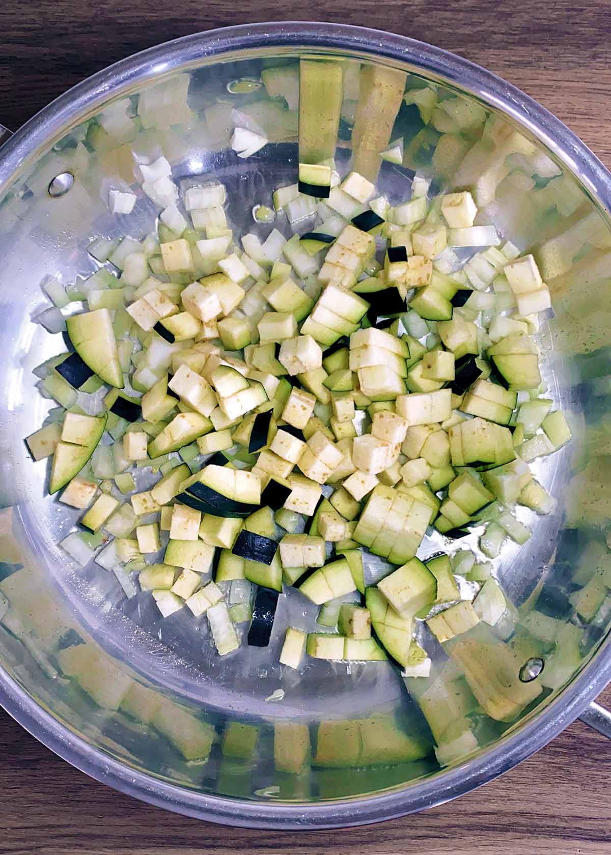 Chopped onions and aubergine cooking in a large pan.