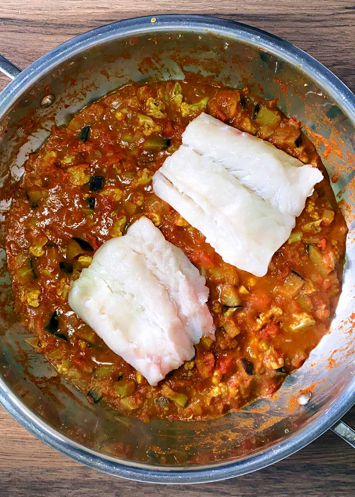 Two cod fillets added to the sauce.