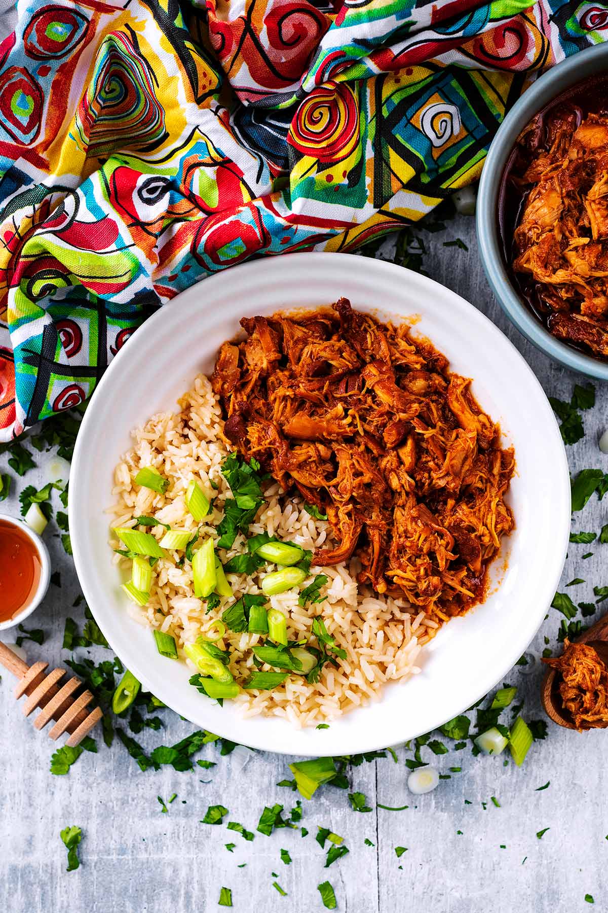 A plate of shredded chicken and rice next to a colourful towel.