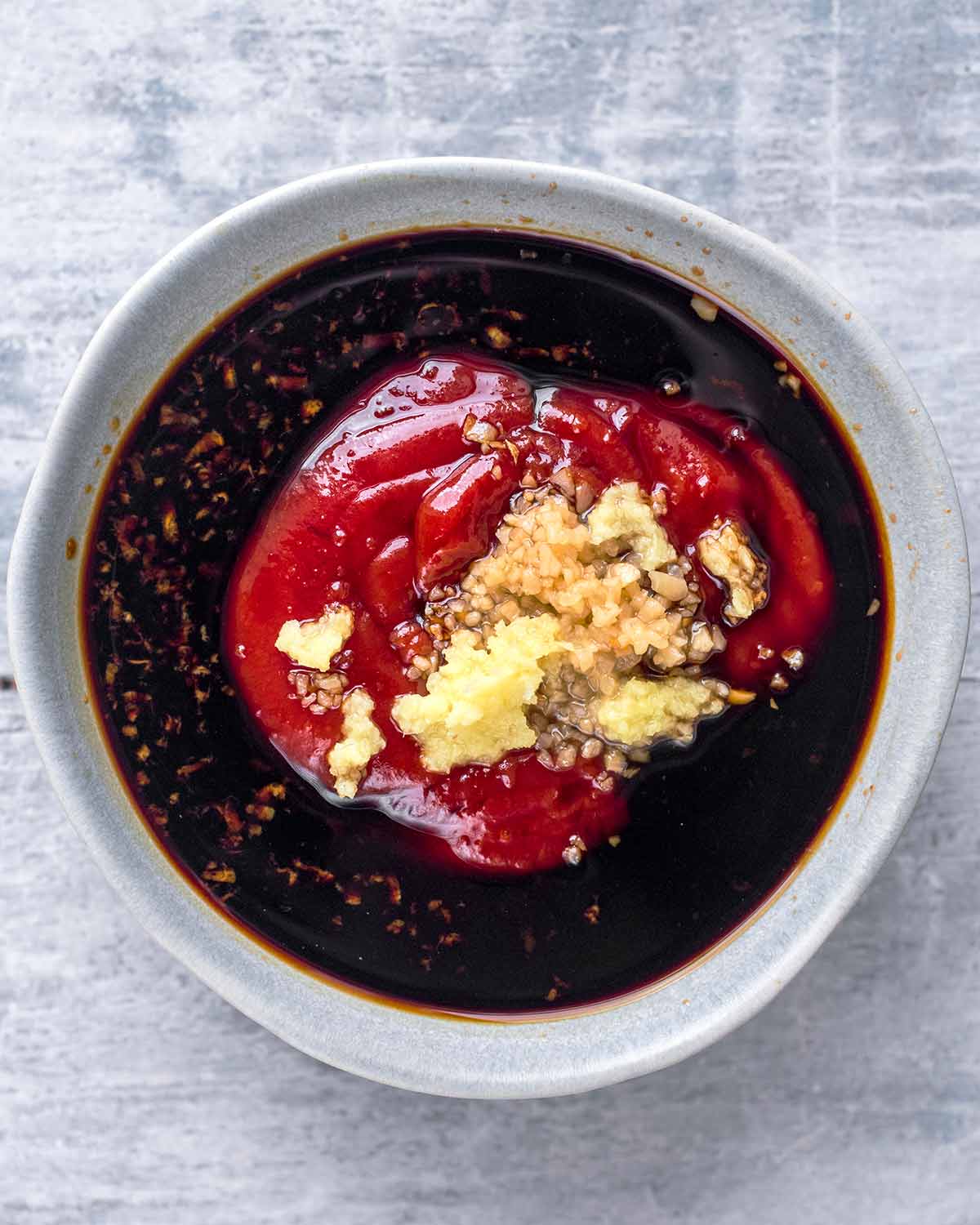 A bowl of soy sauce, honey, garlic, ginger and ketchup.