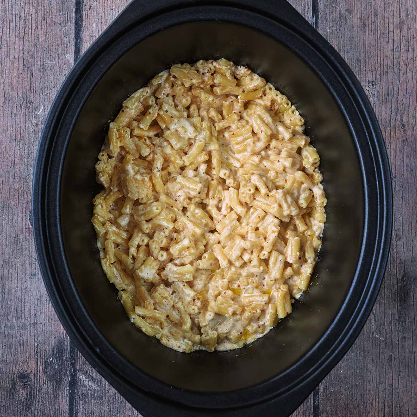 Slow cooker mac and cheese in a black slow cooker bowl.