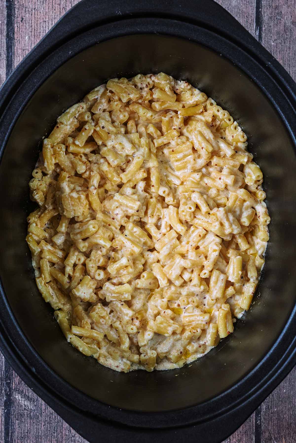 Macaroni cheese in a black slow cooker bowl.