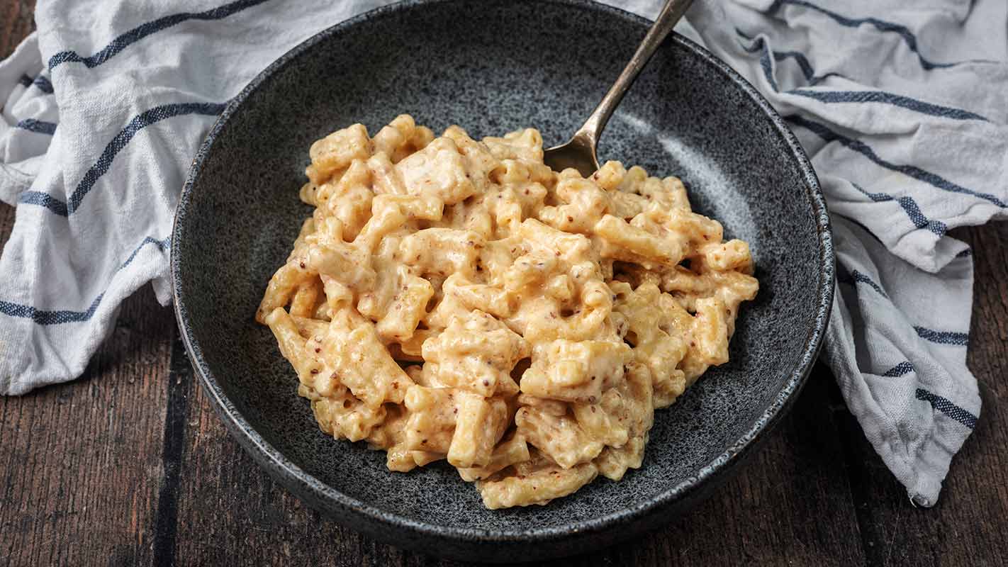 A bowl of slow cooker mac and cheese in front of a striped towel.
