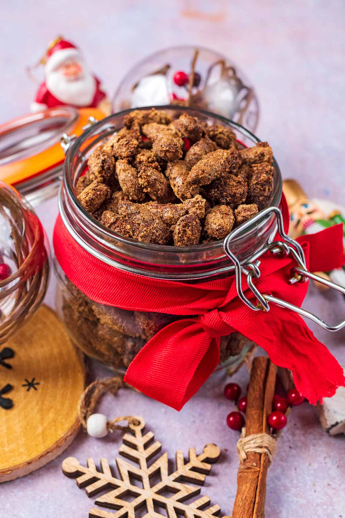 A jar of roasted almonds surrounded by Christmas decorations.