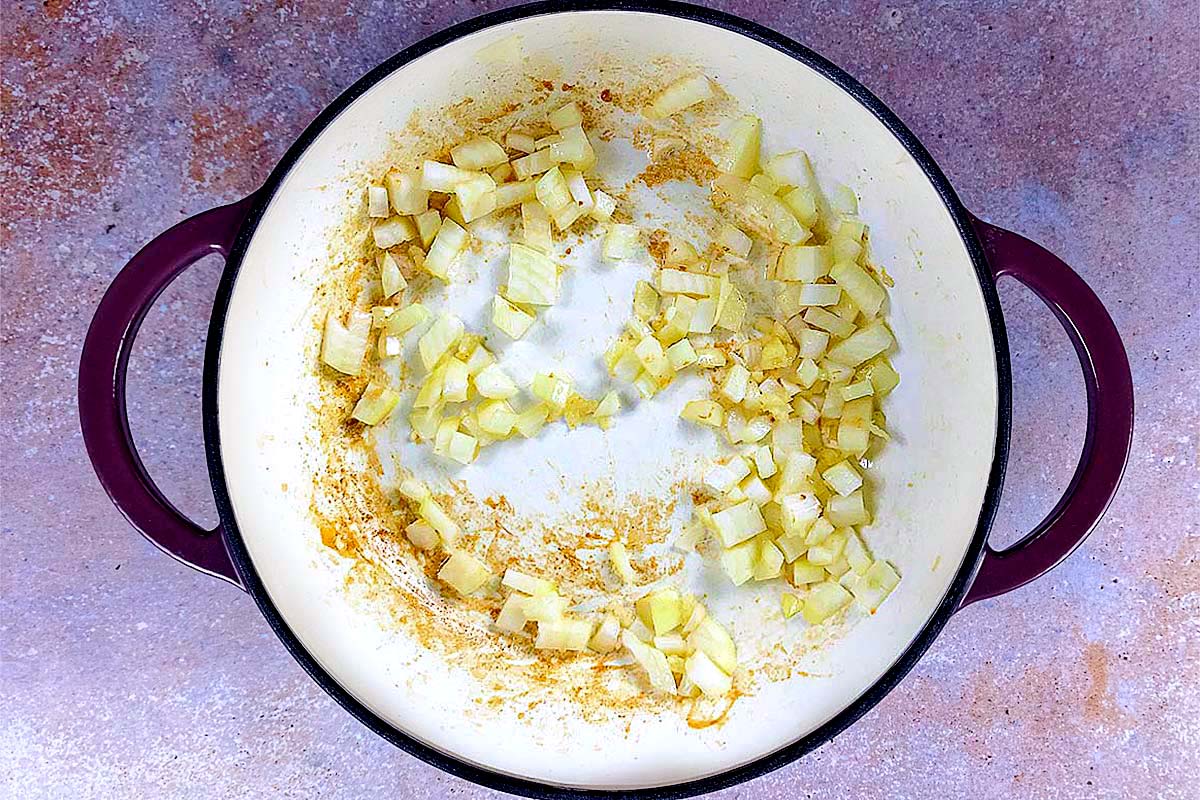 A baking dish with chopped onions cooking in it.