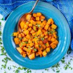 Cubes of roasted butternut squash in a bowl with a spoon.