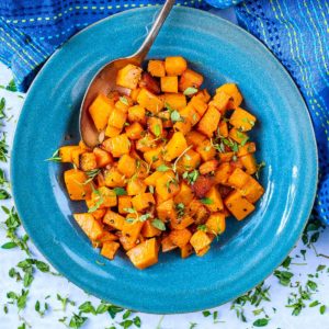 Cubes of roasted butternut squash in a bowl with a spoon.