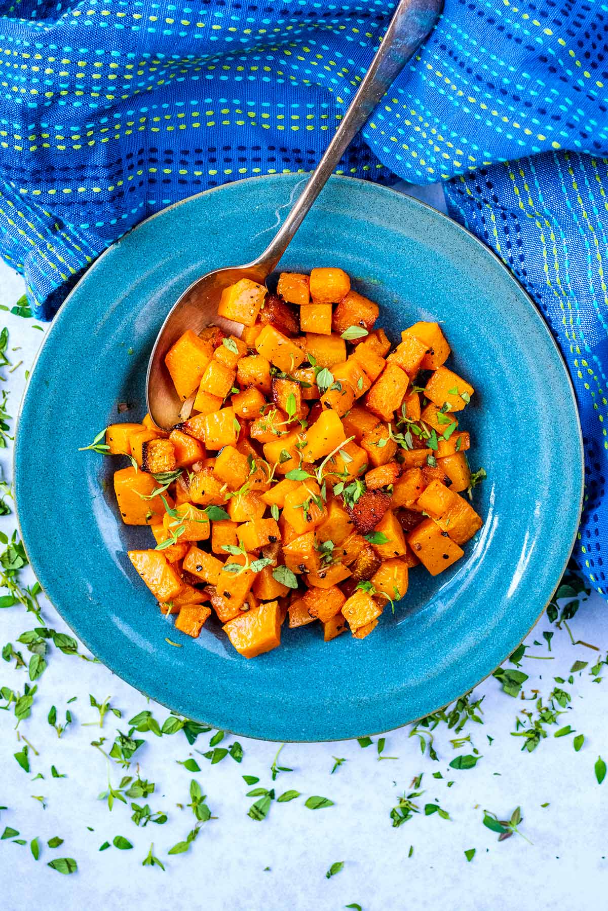 A blue bowl full of cooked cubes of butternut squash.