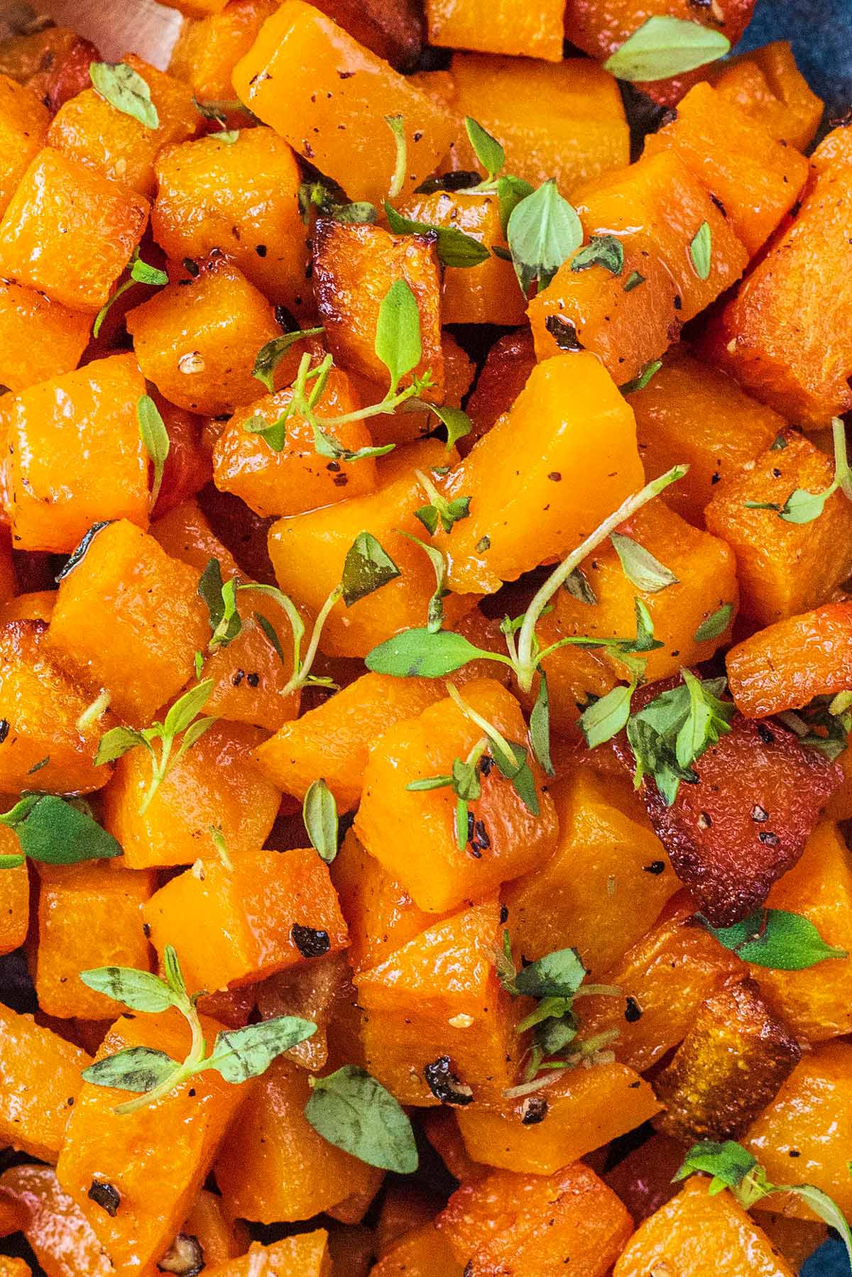 Butternut squash cubes with thyme leaves sprinkled over them.