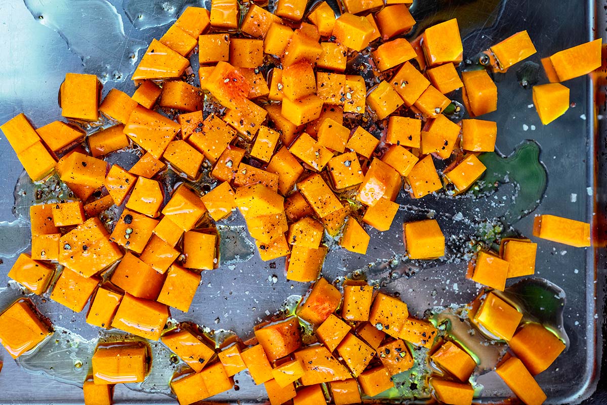 A large baking tray covered in cubes of butternut squash and oil.
