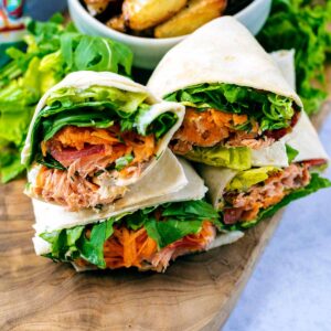 Sliced salmon wrap on a wooden board.