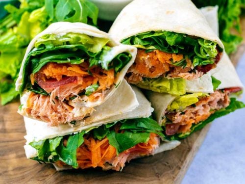 Sliced salmon wrap on a wooden board.