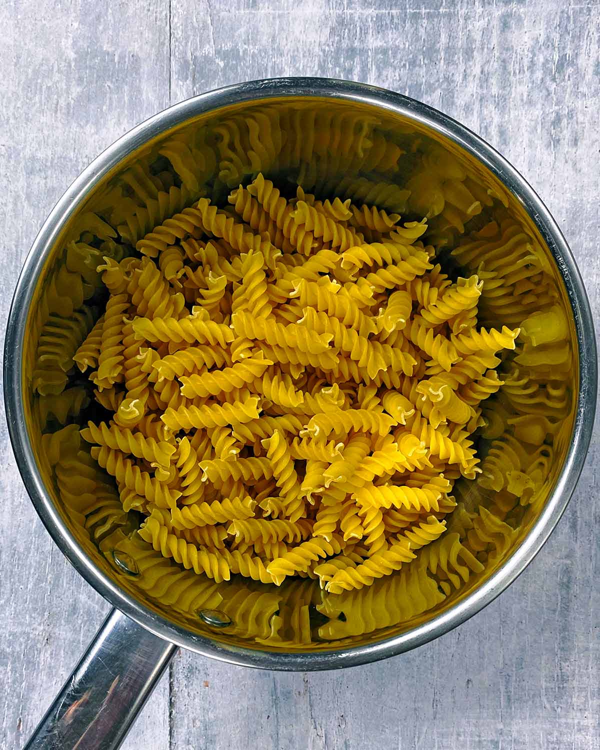 A saucepan containing uncooked fusilli pasta.