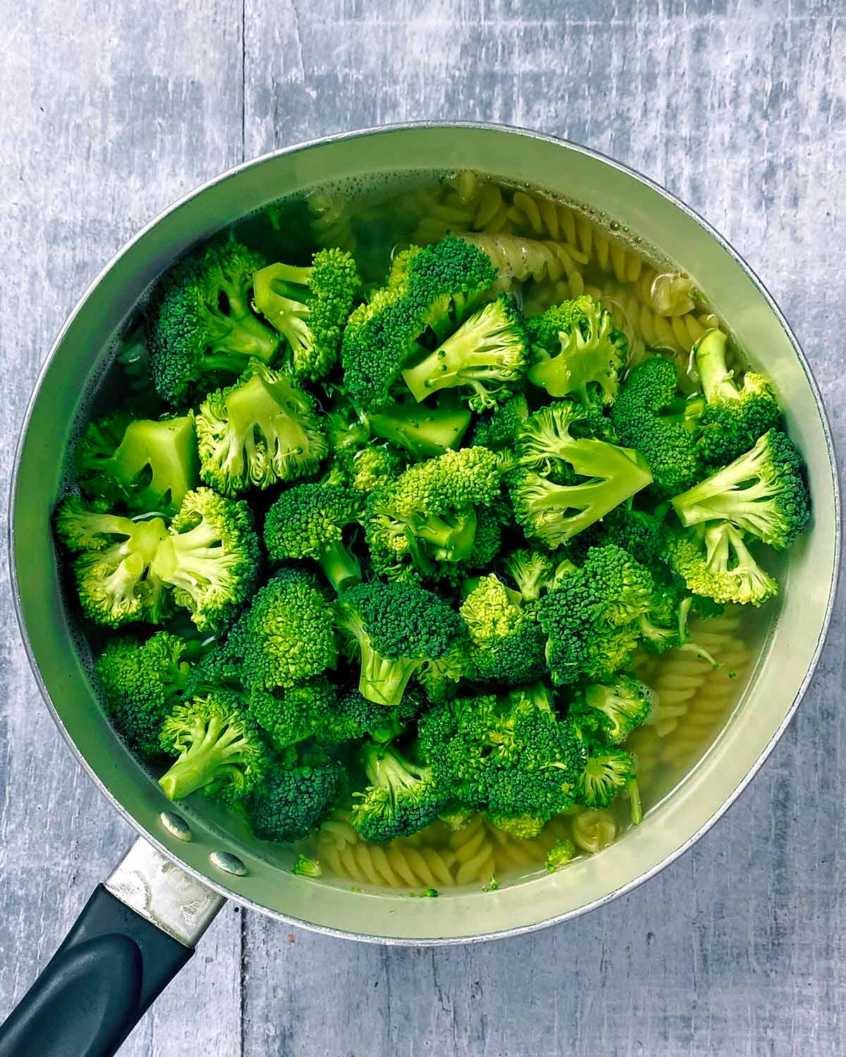 Broccoli florets added to the cooking pasta.