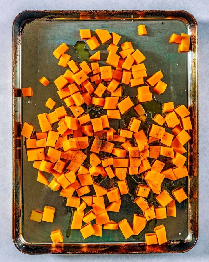 A large baking tray covered in cubes of butternut squash and oil.