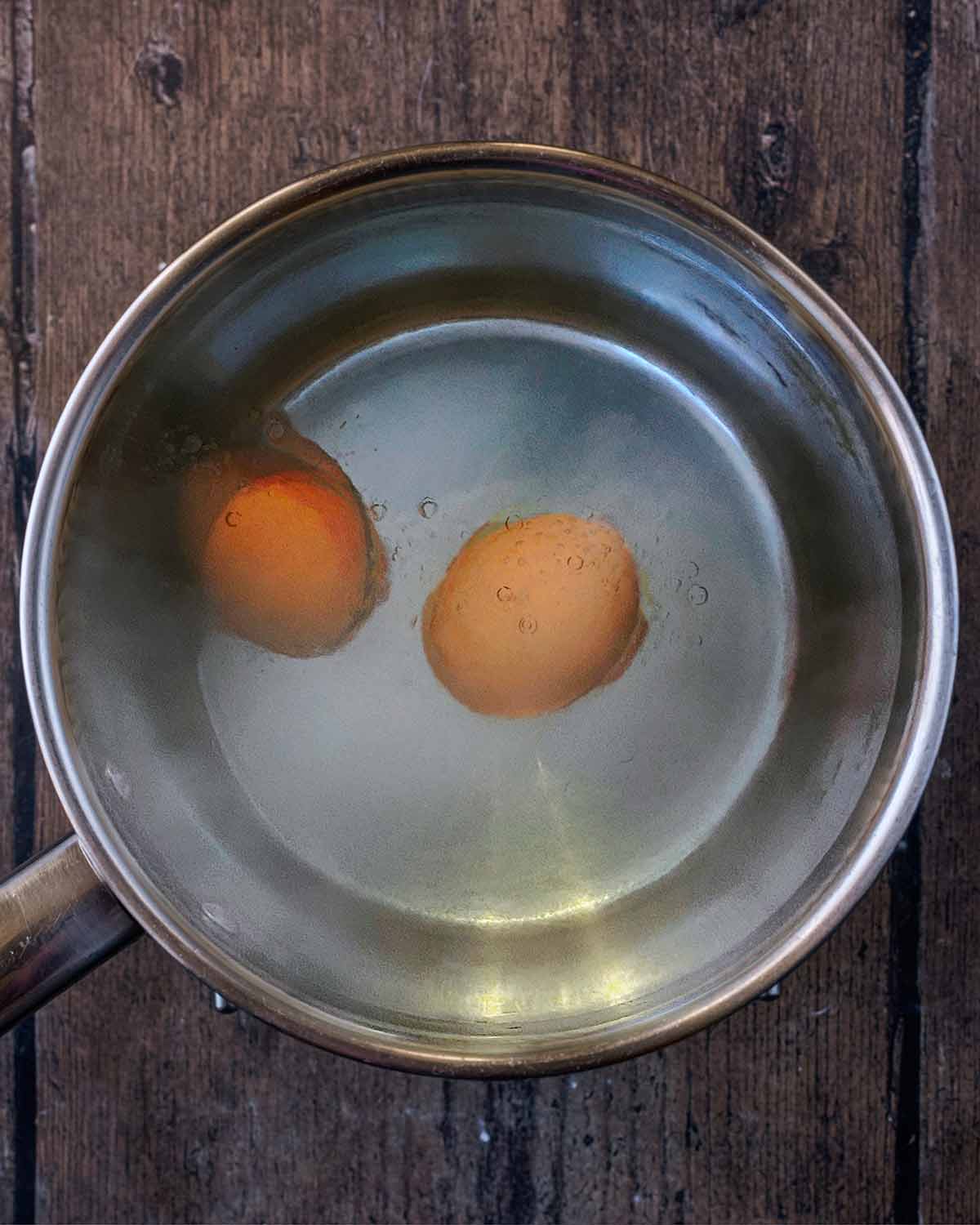 Eggs boiling in a pan of water.