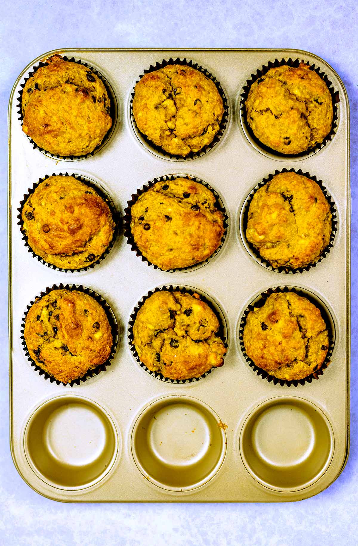 Nine cooked banana muffins in a muffin tin.
