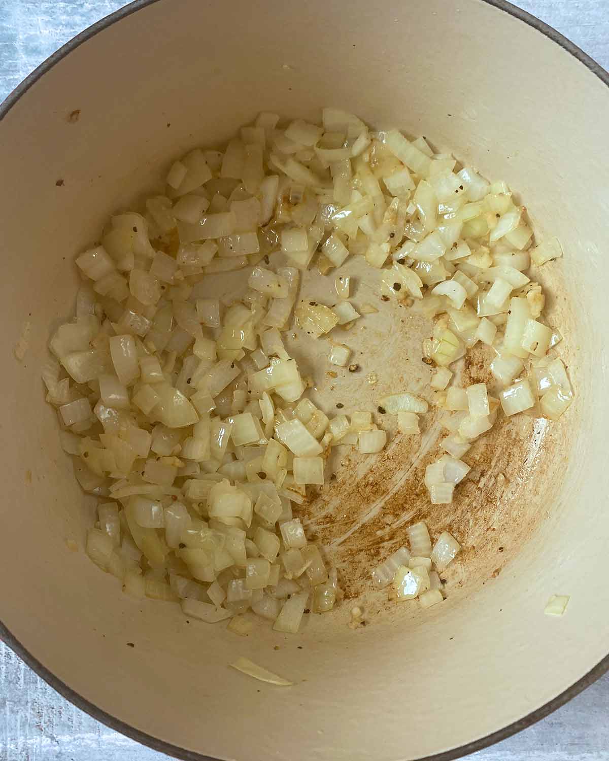 A large cooking pot with chopped onions cooking in it.