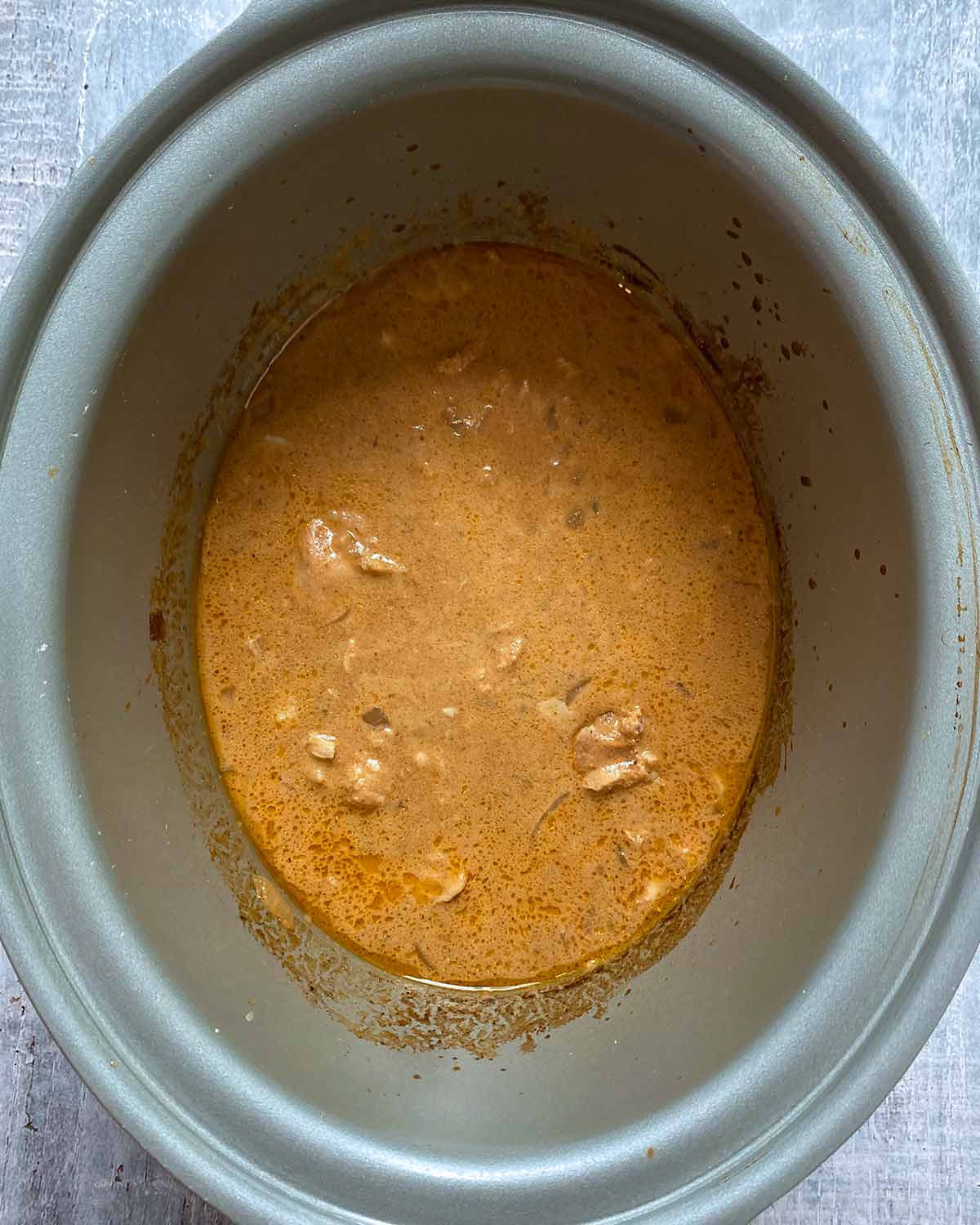A cooked chicken curry in a slow cooker pot.