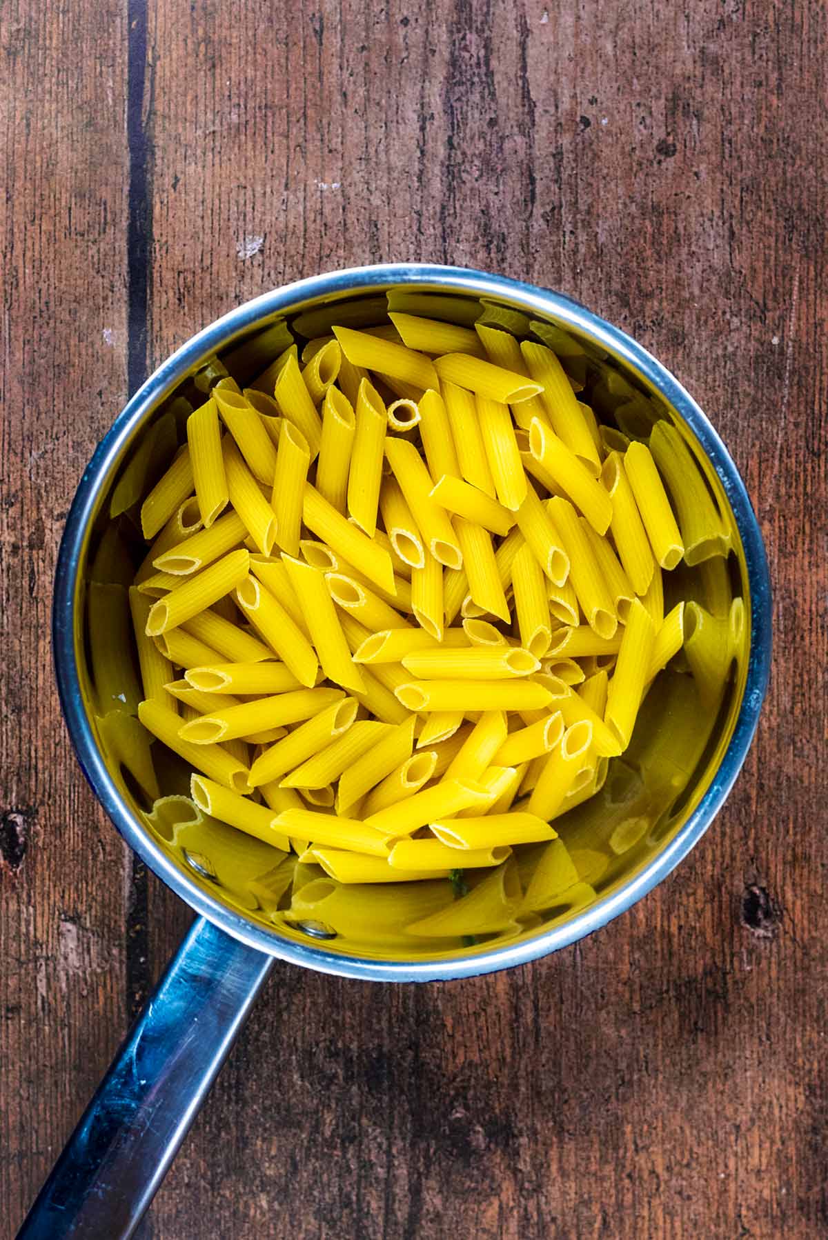 A saucepan full of uncooked penne pasta.