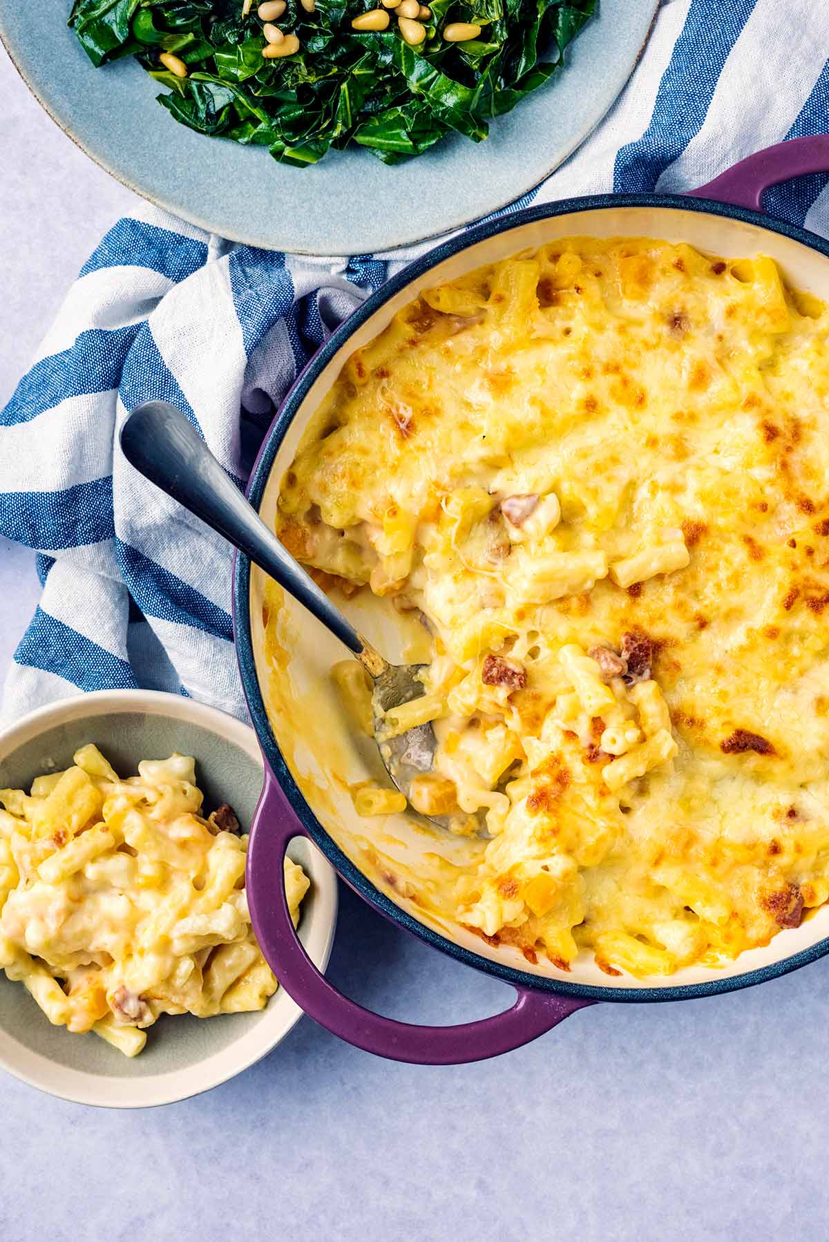 A large dish full of macaroni cheese with a portion removed and put in a small bowl.