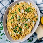Easy Marmite Pasta in a bowl topped with cheese and chopped herbs.