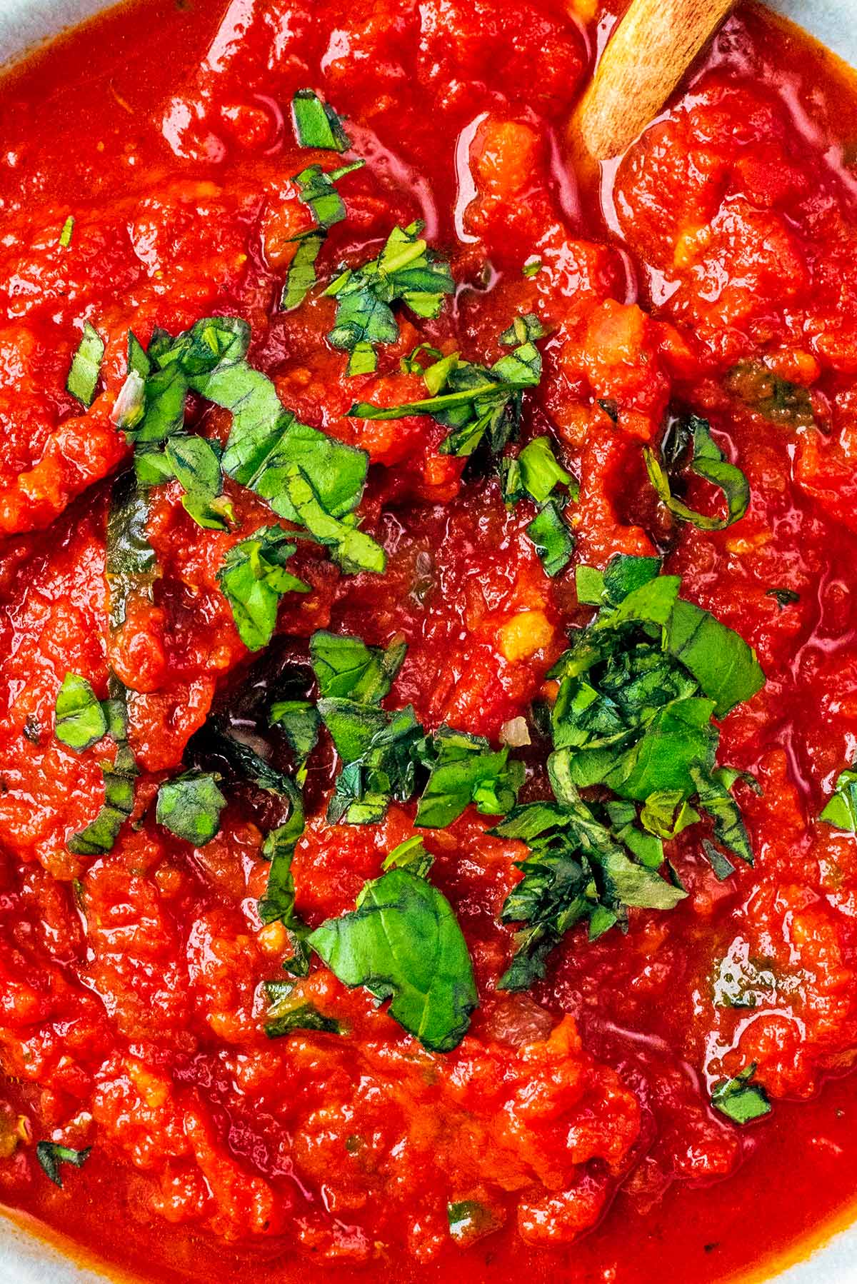 Pizza sauce topped with chopped basil.