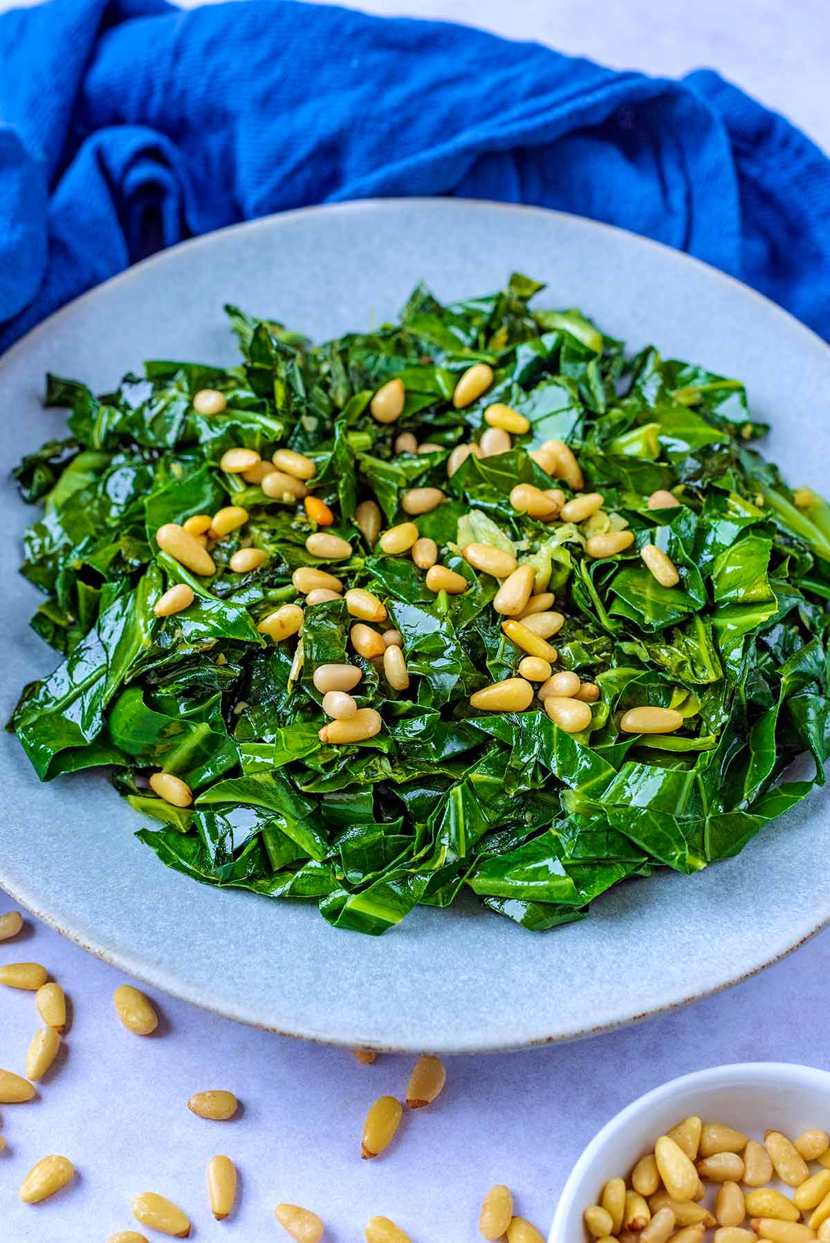 A plate of cooked spring greens in front of a blue towel.