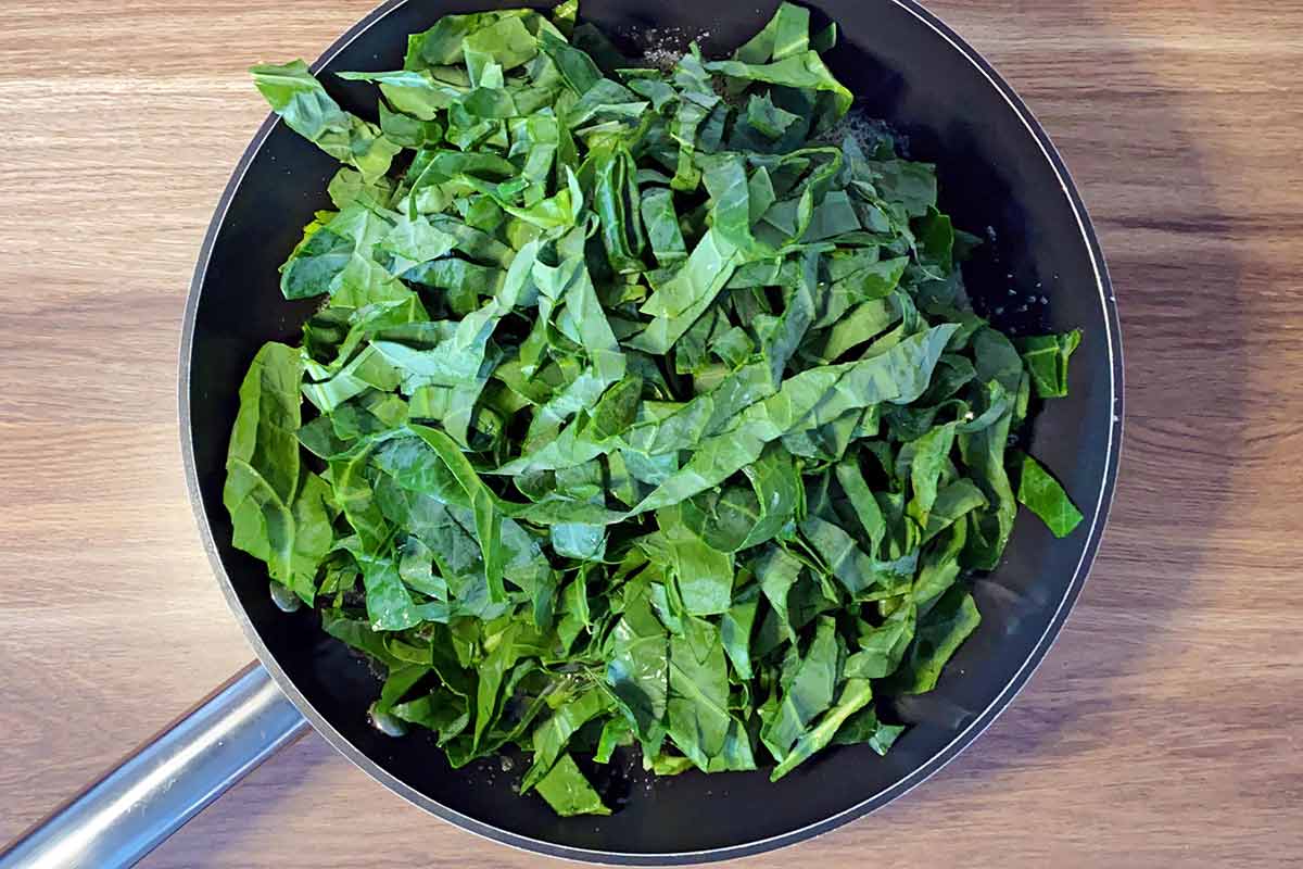 Shredded spring greens added to the pan.