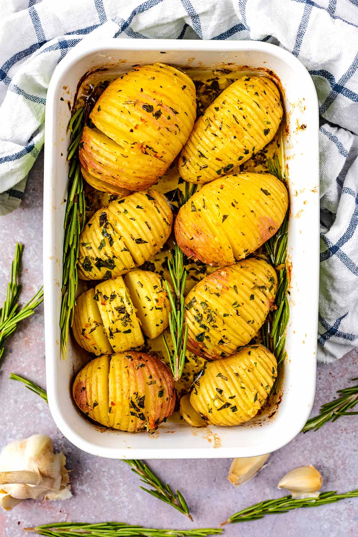 A baking dish containing eight cooked hasselback potatoes.