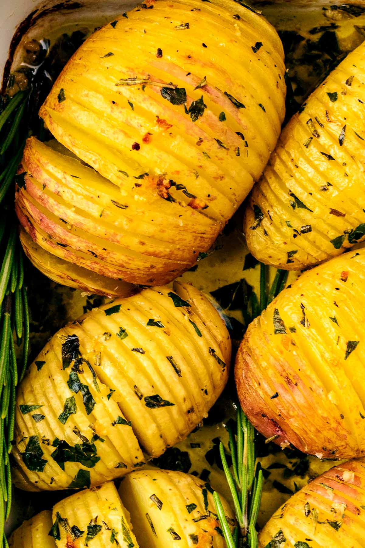 Cooked hasselback potatoes topped with chopped herbs.