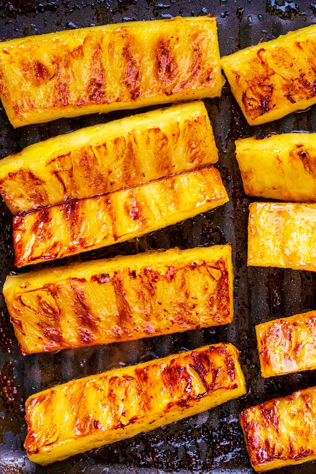 Pineapple sticks cooking on a griddle pan.