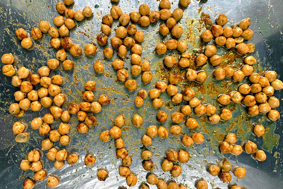 Coated chickpeas spread over a baking tray.