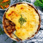 Sausage and mash pie in a large serving dish with sprigs of thyme on top.