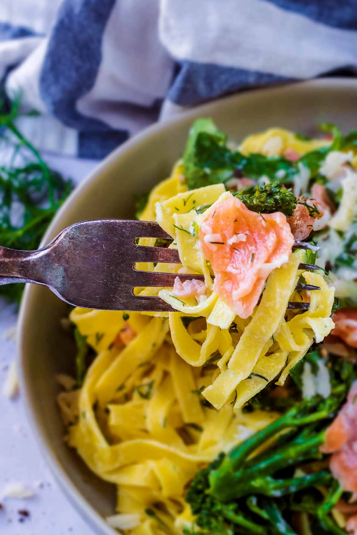 A fork picking up some pasta and smoked salmon.