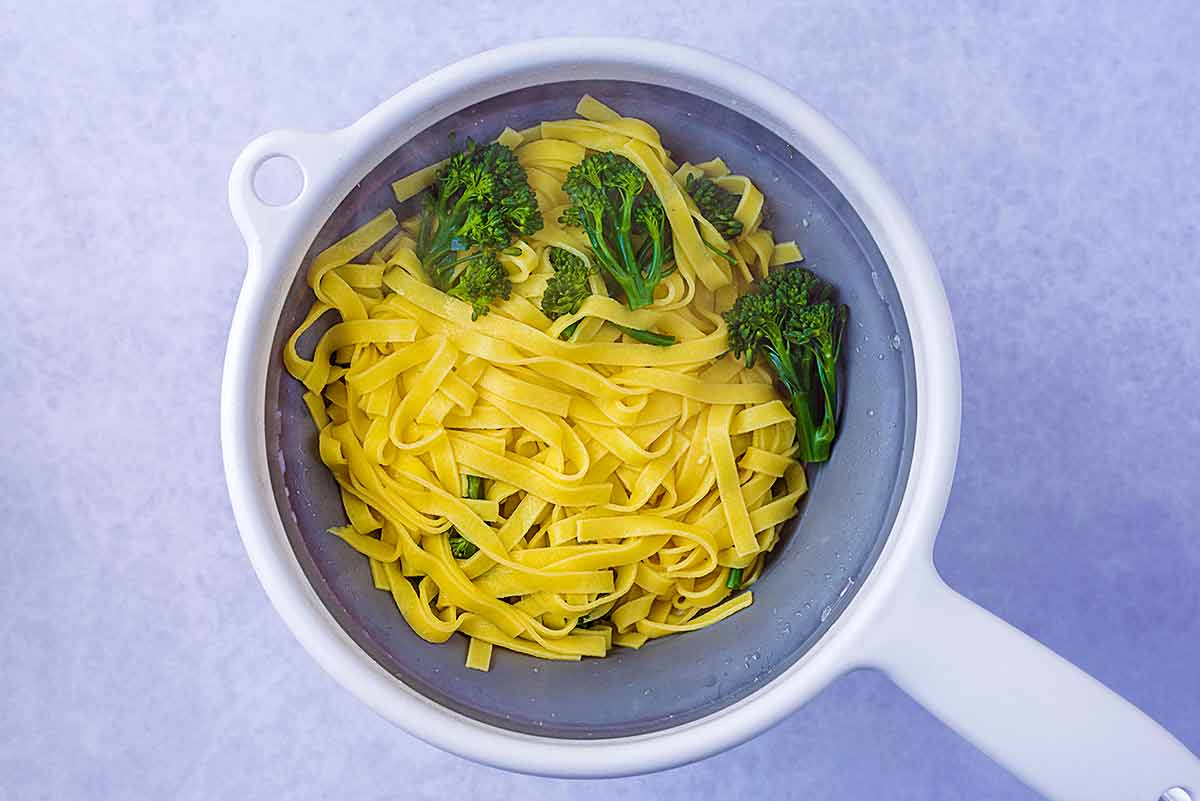 Cooked tagliatelle and broccoli in a colander.