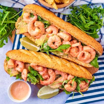 The best prawn sandwich on a striped napkin next to bunches of salad leaves.