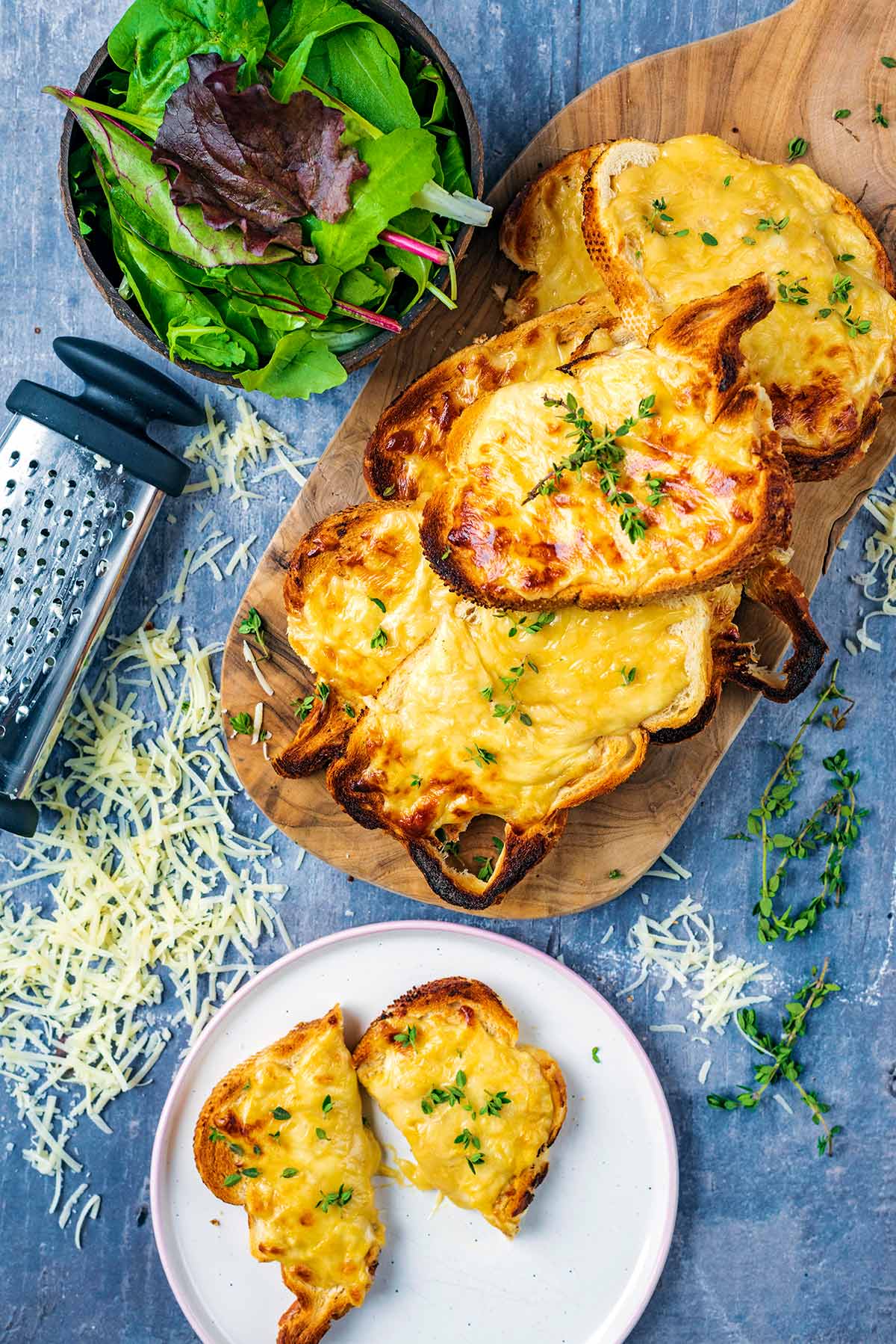 Slices of Welsh Rarebit on a board with a cut slice on a plate.