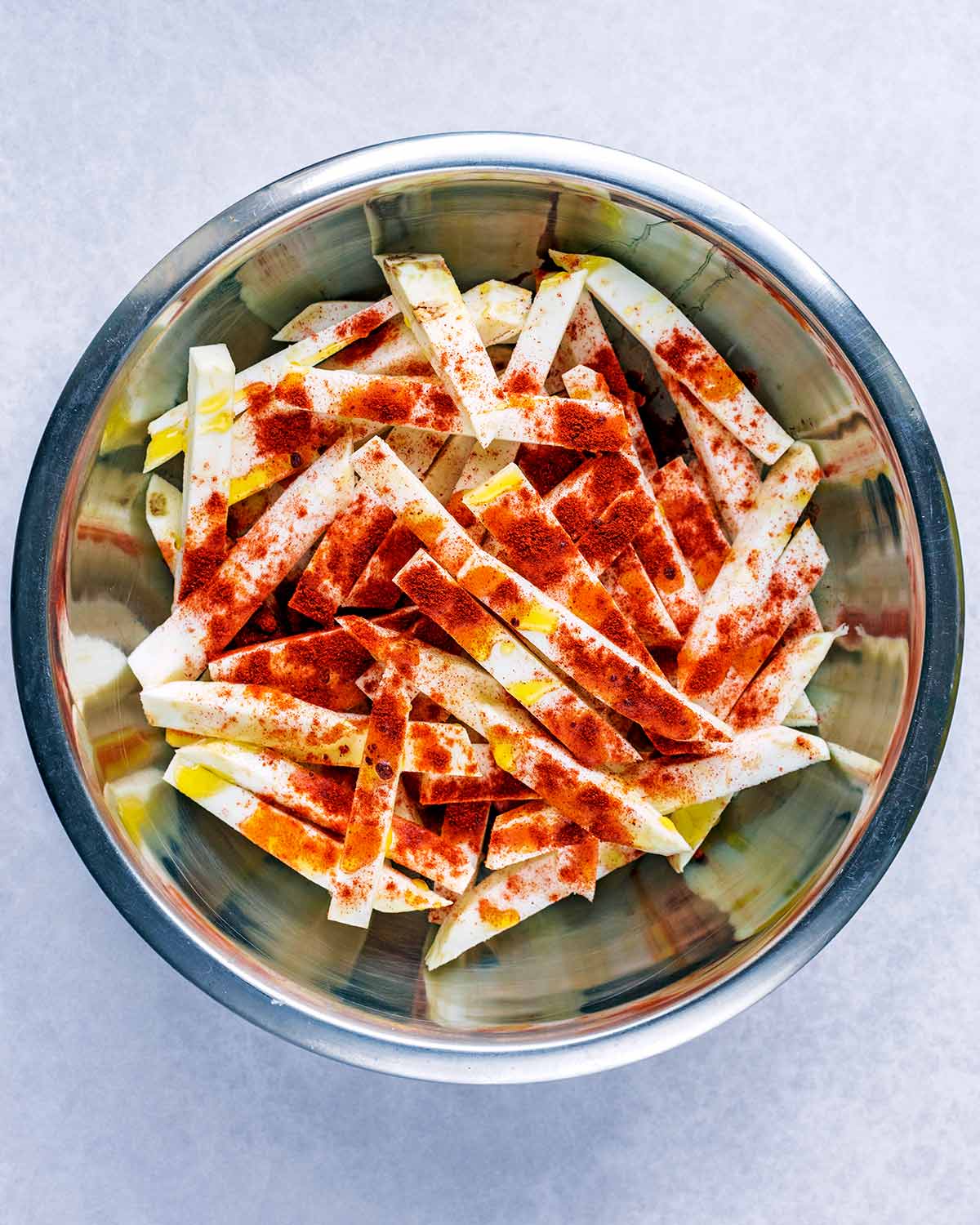 Uncooked celeriac chips coated in paprika.