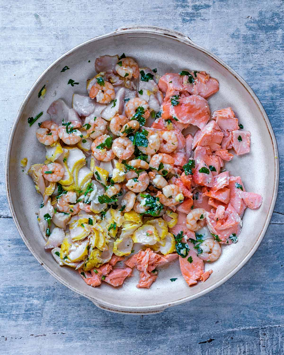 A large baking dish containing milk and flaked fish.