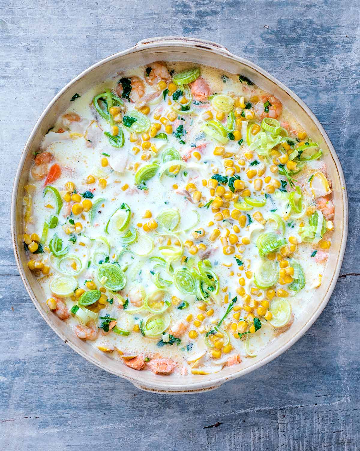 The milk and vegetable mixture pored over the fish in the baking dish.