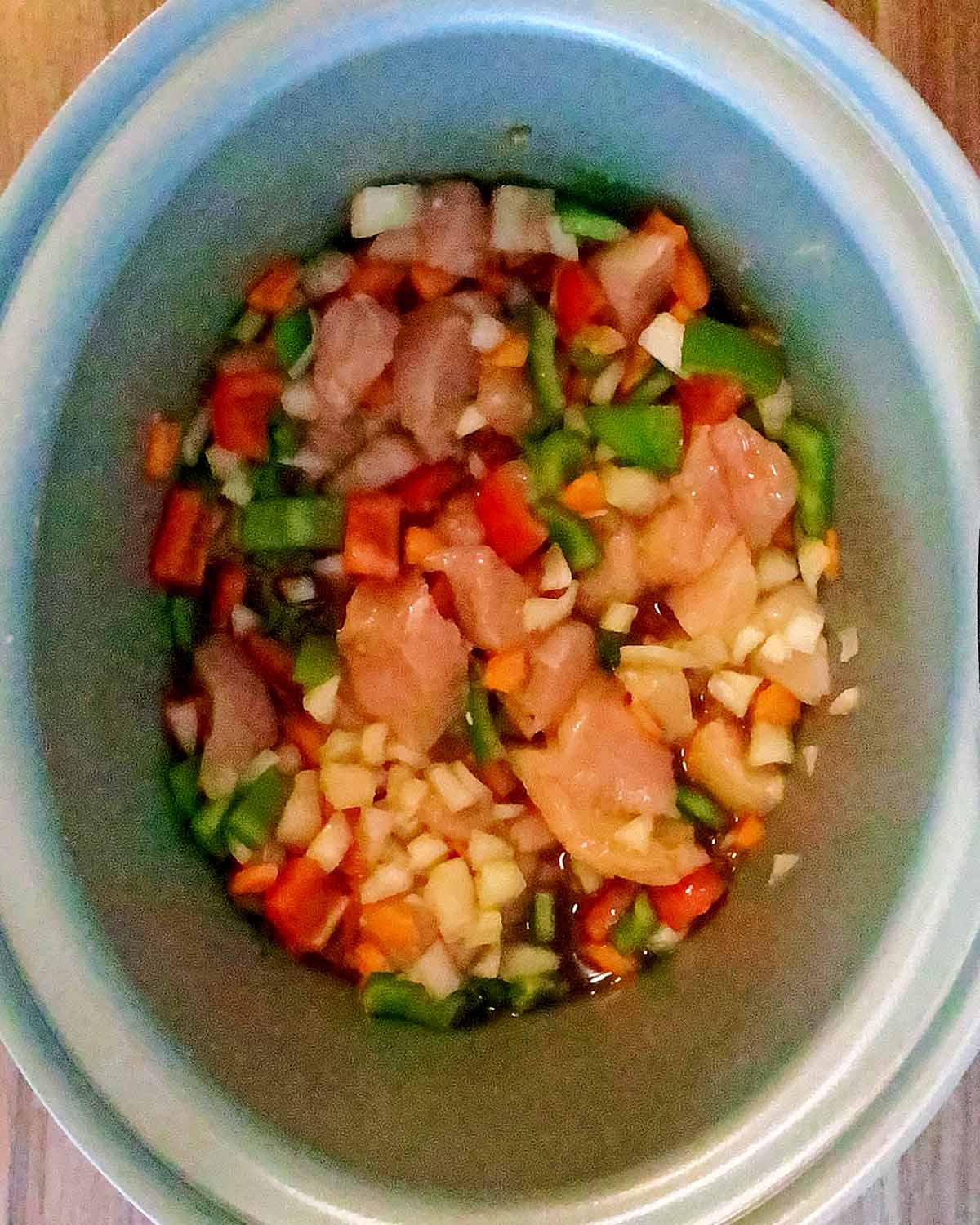 Chicken and vegetables in a slow cooker with sauce poured over.