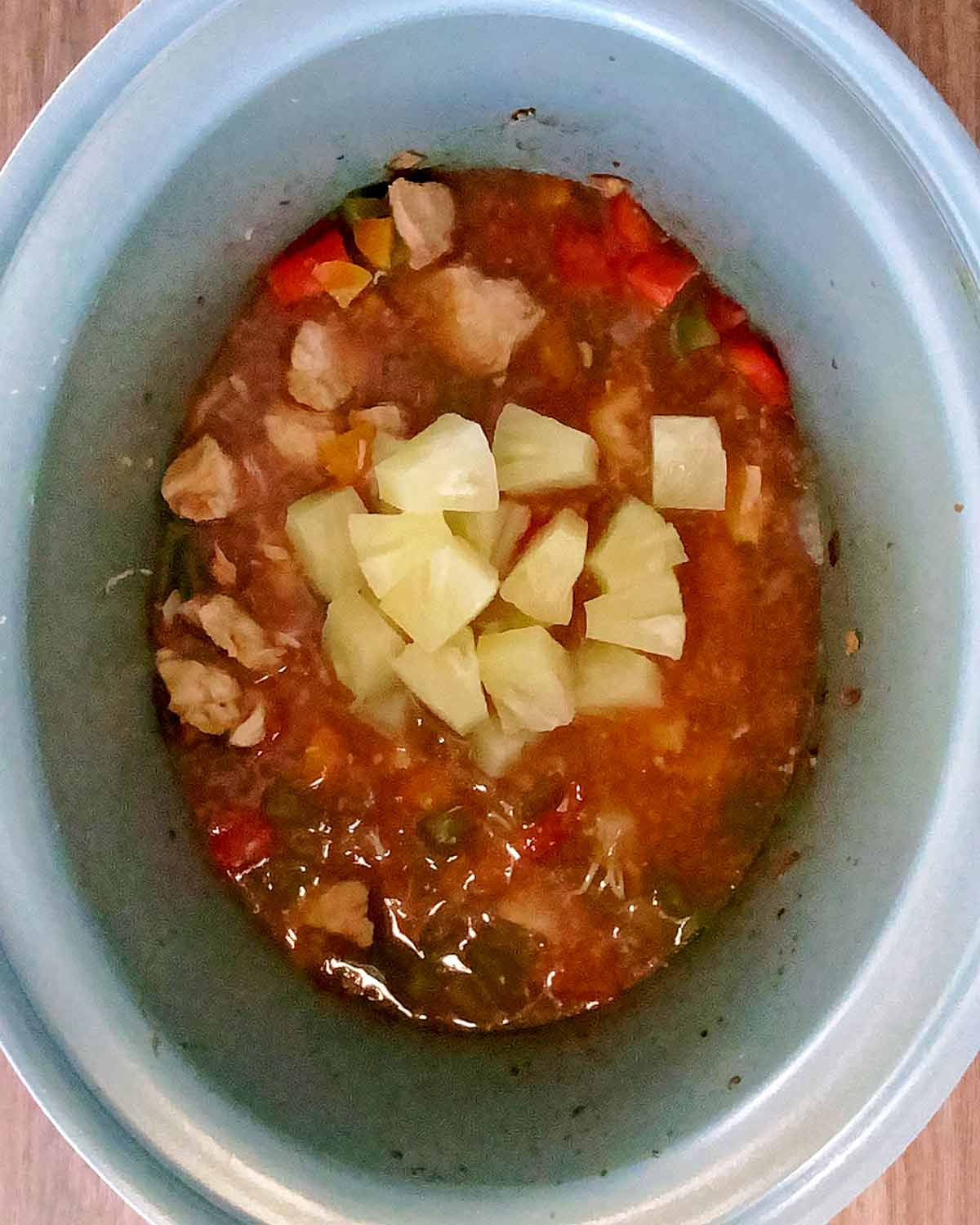 Pineapple chunks added to the slow cooker.