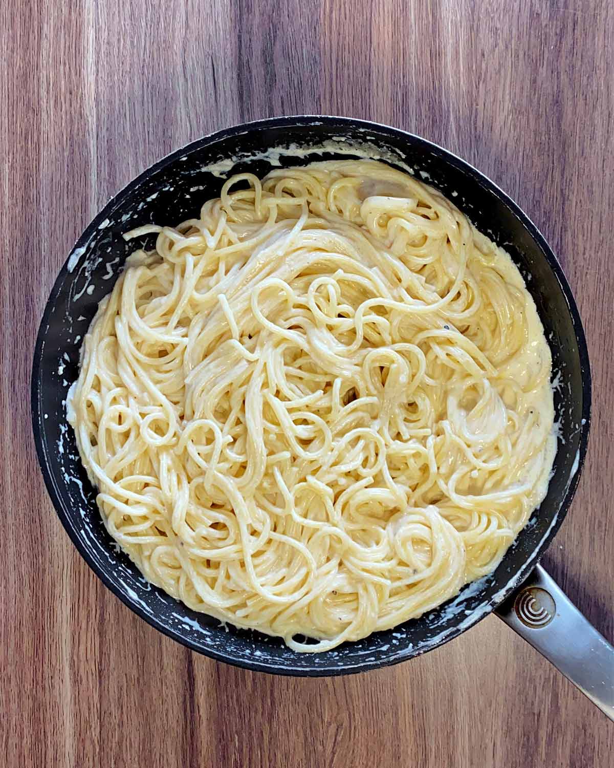 The spaghetti mixed into the cheese sauce.