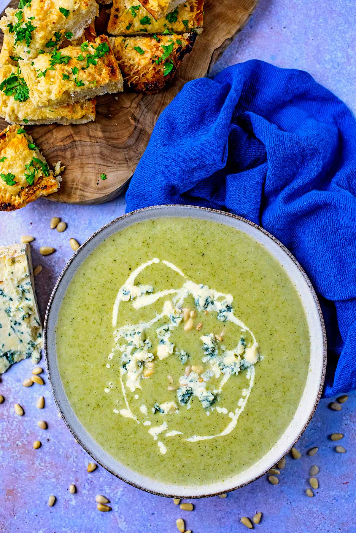 A bowl of soup next to some cheese and some garlic bread.