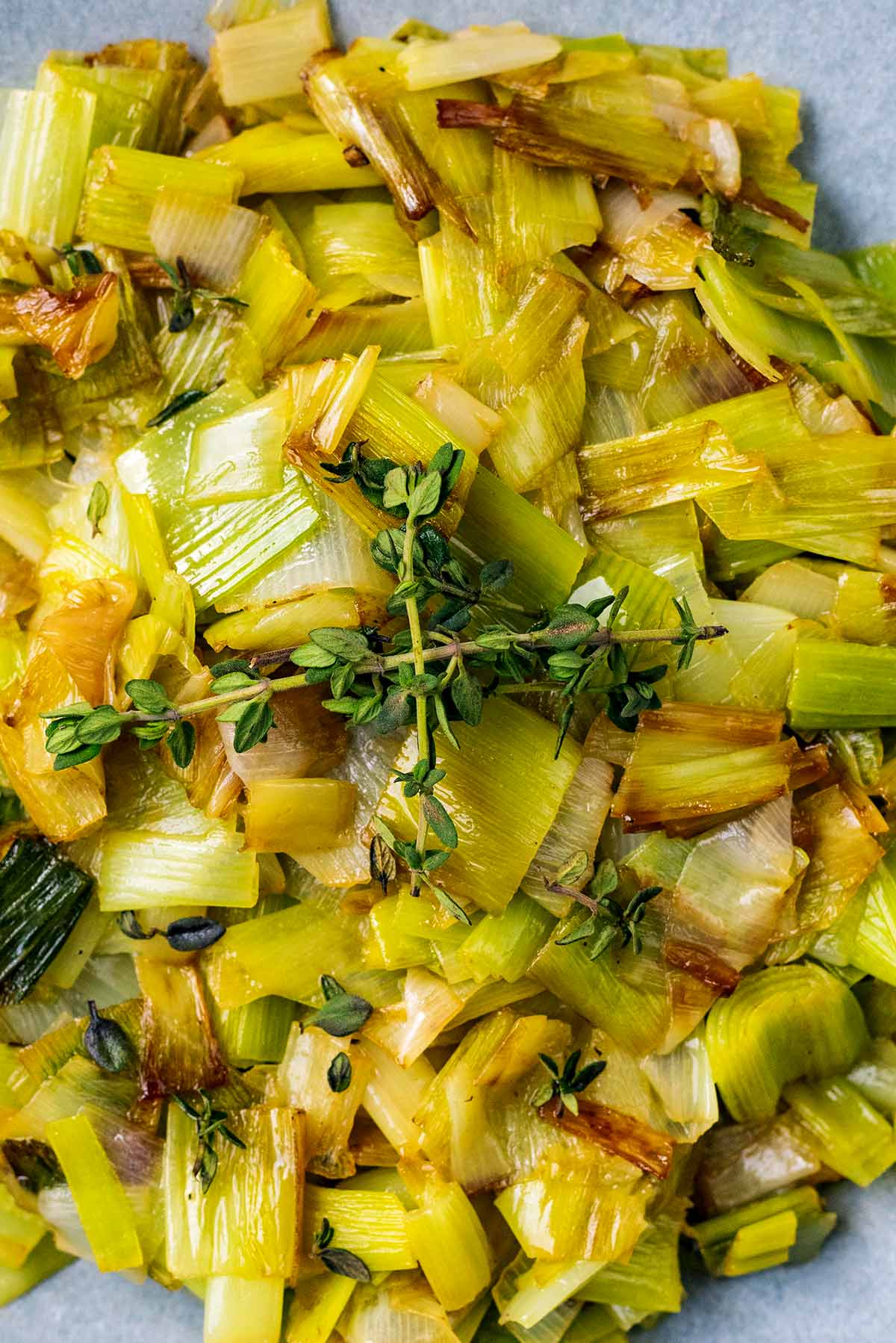 Cooked chopped leeks with two sprigs of thyme on top.