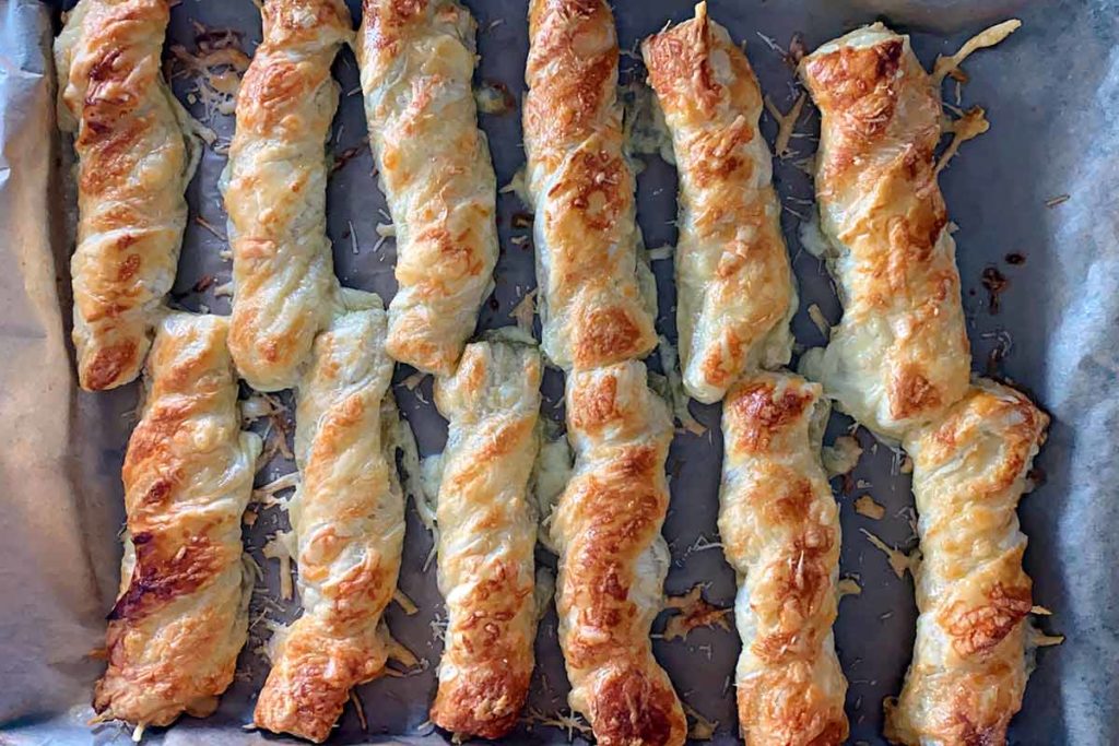 Cooked cheese straws on a baking tray.