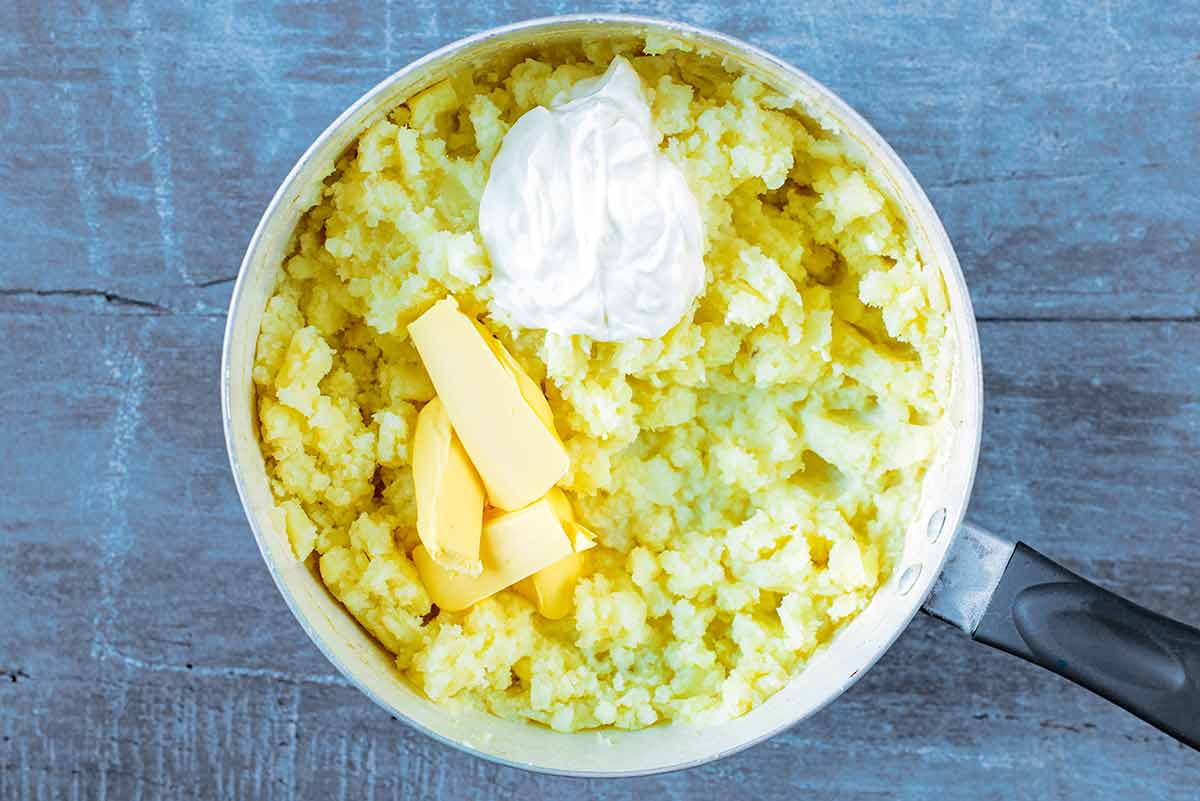 A saucepan containing mashed potato, butter and cream.