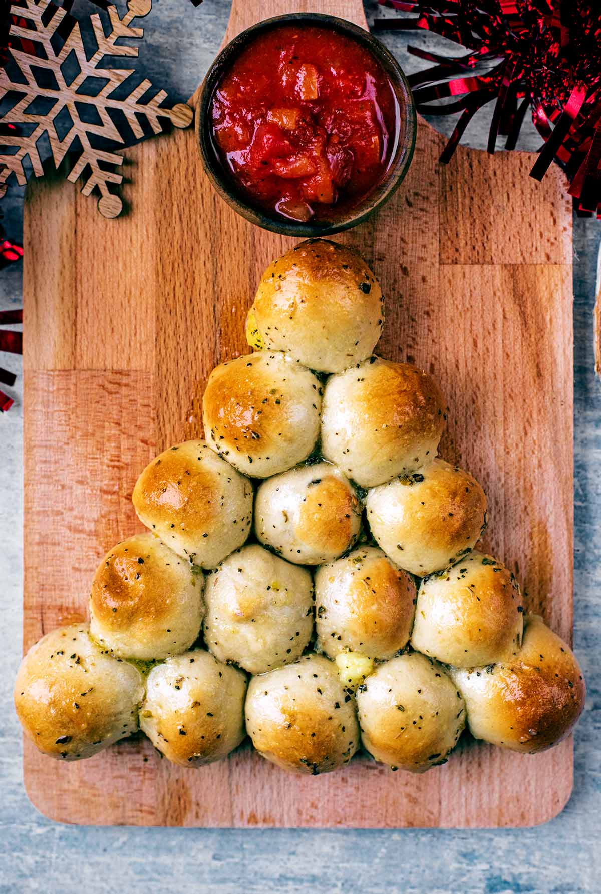 Fifteen baked dough balls in a triangle shape on a wooden board.
